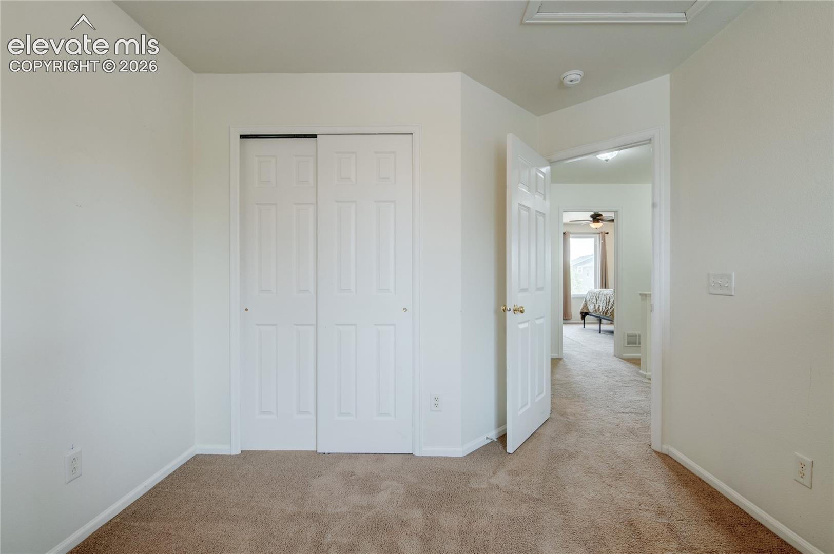 Carpeted room featuring a white bi-fold closet and a classic white paneled door