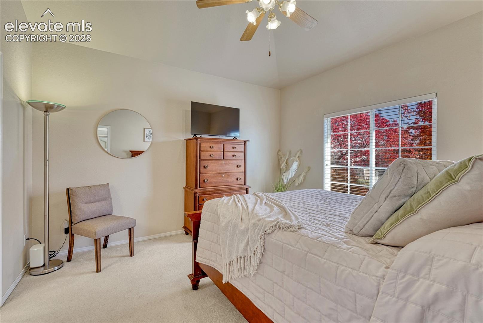 The spacious primary bedroom easily accommodates large furniture and offers a bright window framing colorful autumn views
