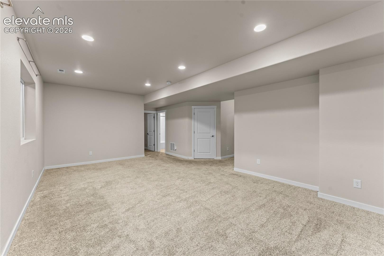 Neutral-toned interior space featuring recessed ceiling lighting, wall-to-wall carpeting, and solid-core interior doors