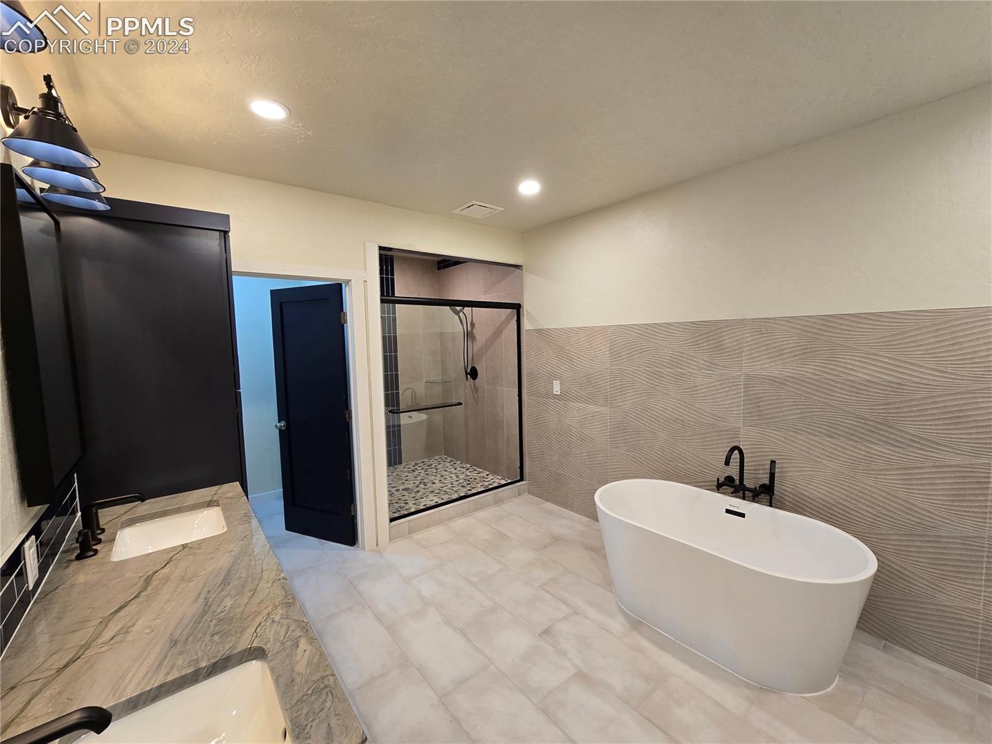 Lower level bathroom with tile walls, independent shower and soaking tub, and vanity