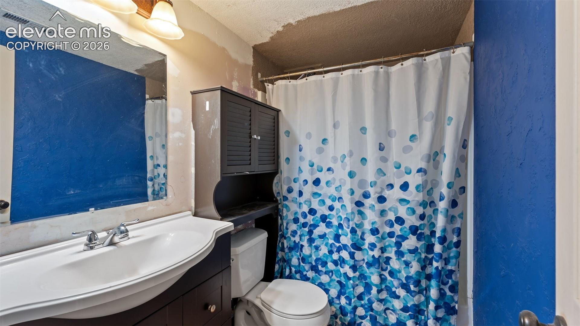 Bathroom featuring a wall-mounted vanity with a porcelain sink, polished chrome faucet, rectangular mirror, and an integrated storage cabinet