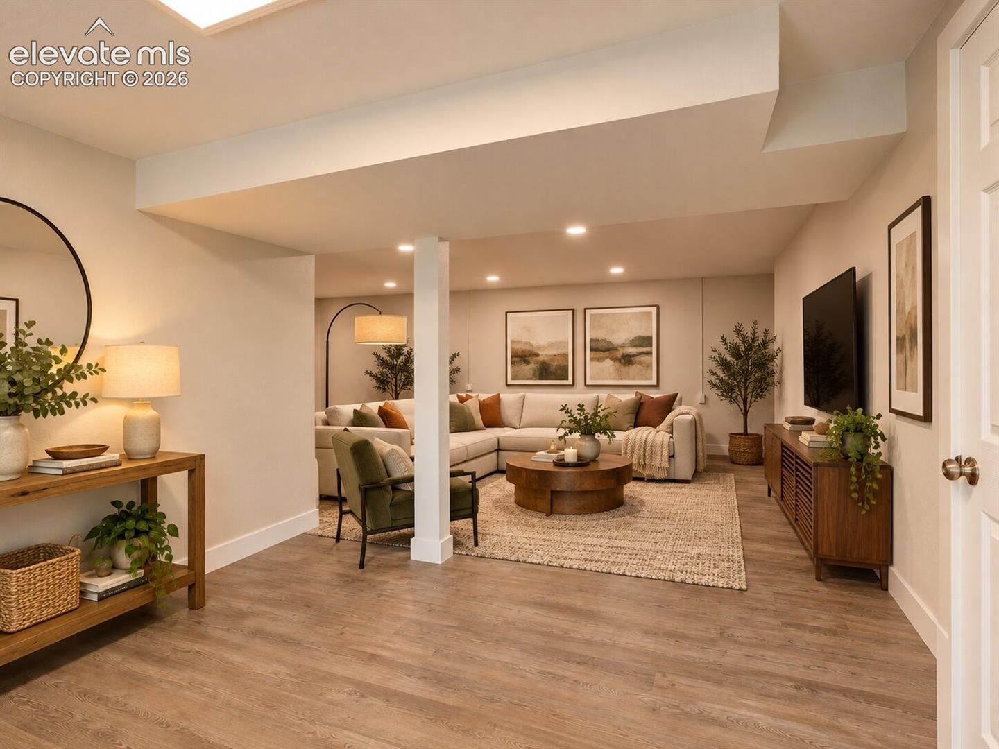 Finished interior space featuring wood-finish flooring, recessed lighting, and a central support column. AI-Enhanced – furniture/decor digitally added