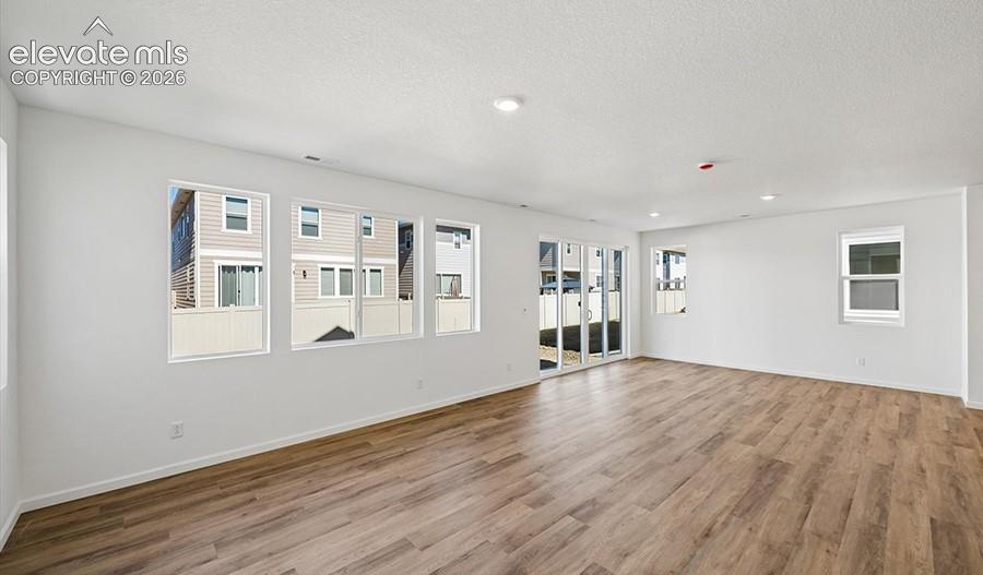 Open-concept room featuring neutral wall finishes, wood-finish flooring, multi-pane windows, and sliding glass doors