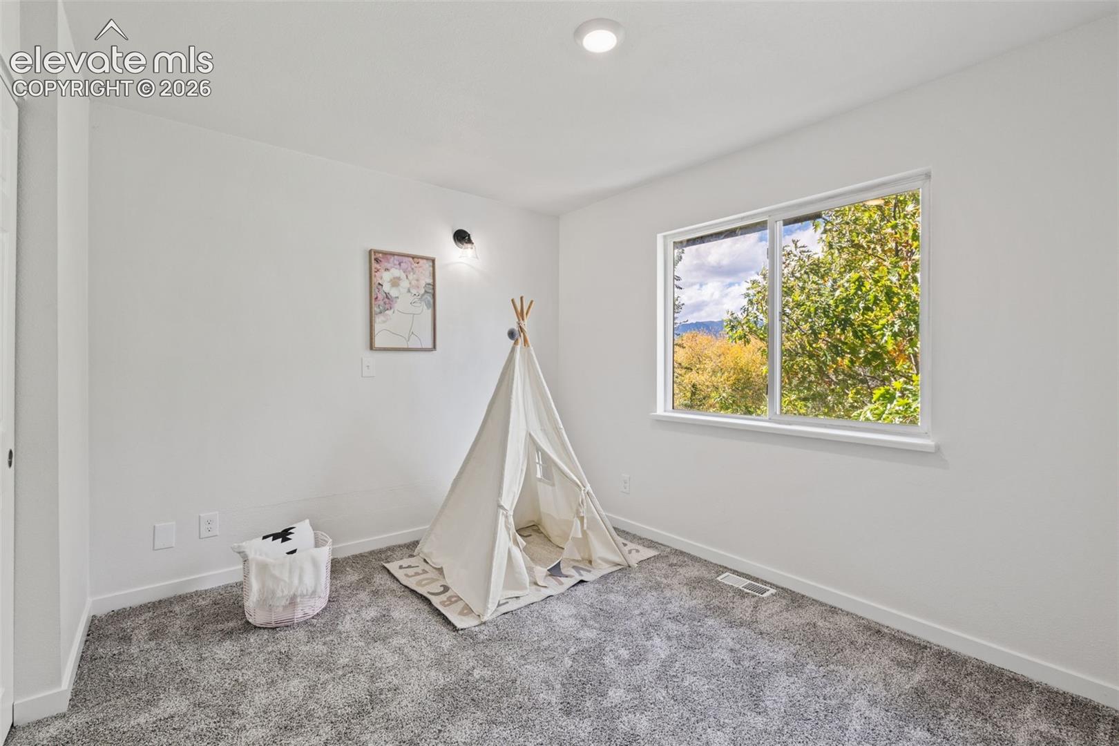 Bright room featuring neutral wall paint, gray carpeting, a single-pane sliding window, and a recessed ceiling light