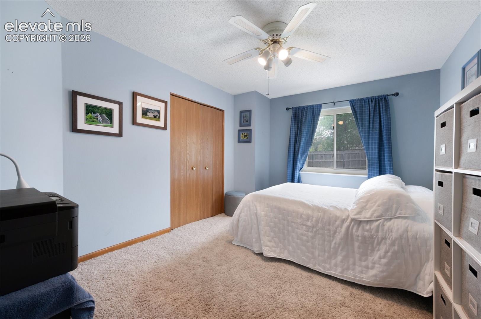 Bedroom with carpet, a textured ceiling, a closet, and a ceiling fan