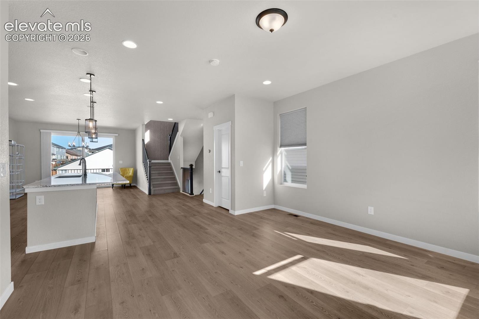 Wood-finish flooring, recessed lighting, and a kitchen island with a stone countertop
