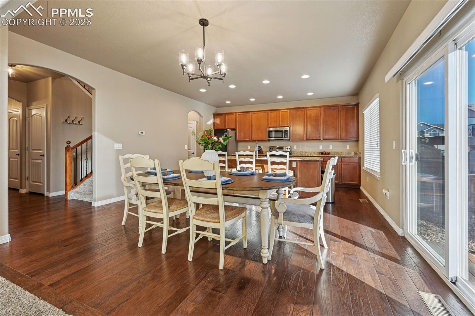 Dining space with arched walkways, dark wood finished floors, and hanging lights