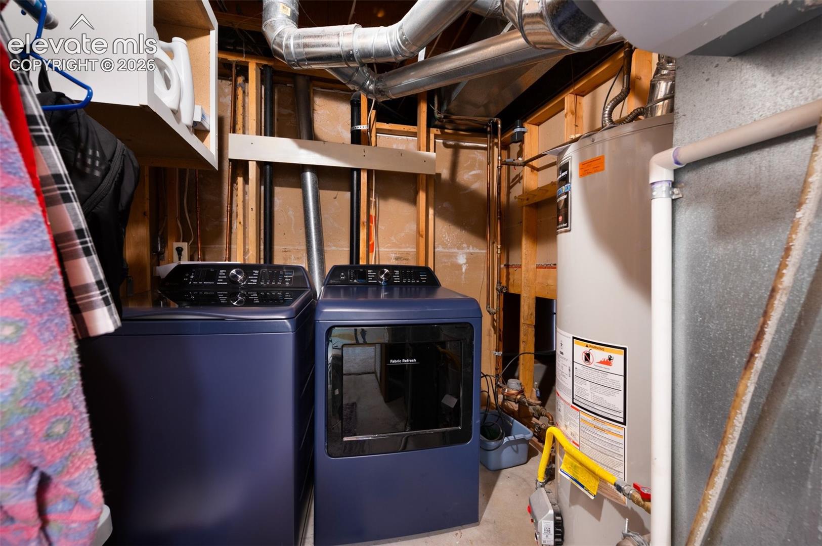 Clothes washing area featuring water heater and washer and clothes dryer