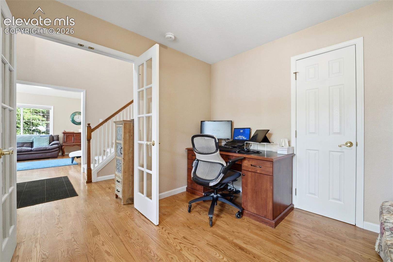 Office space featuring light wood-finish flooring, neutral-toned walls, and French doors
