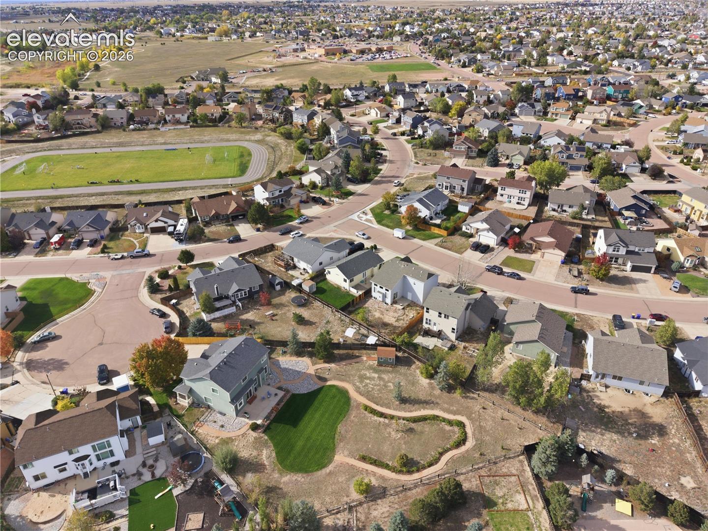 Expansive neighborhood featuring residential homes, paved streets, and a green athletic field with a track