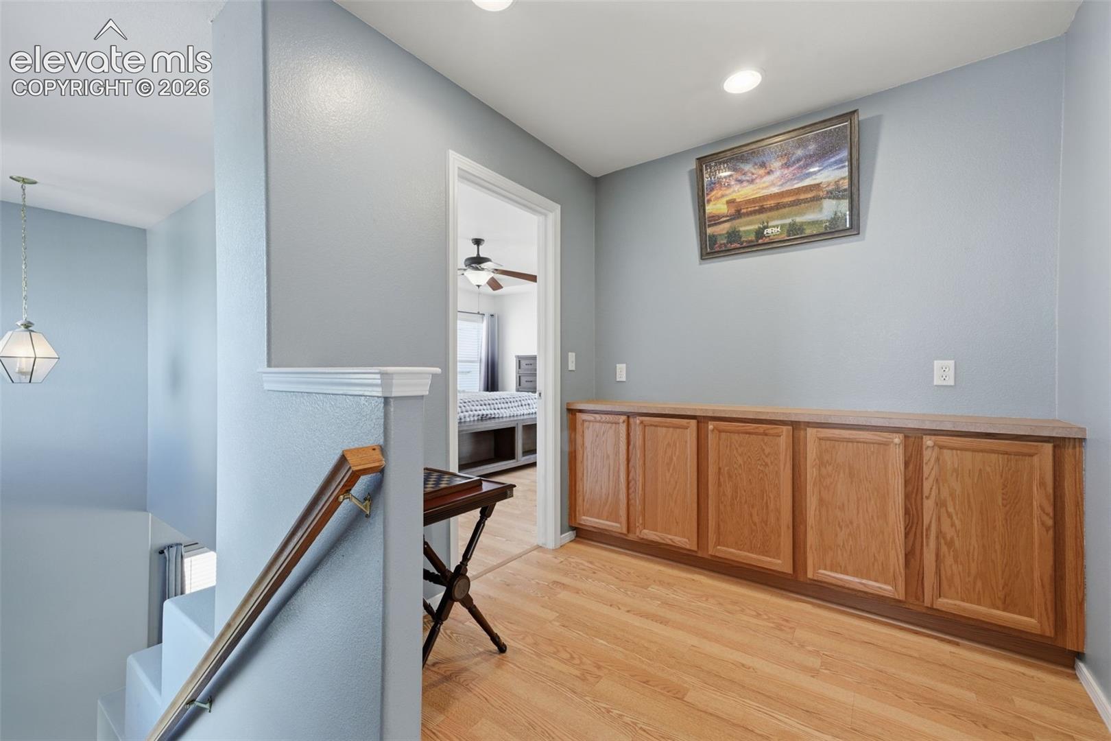 Wood-finish flooring, built-in wooden cabinetry, recessed lighting, and a suspended geometric light fixture