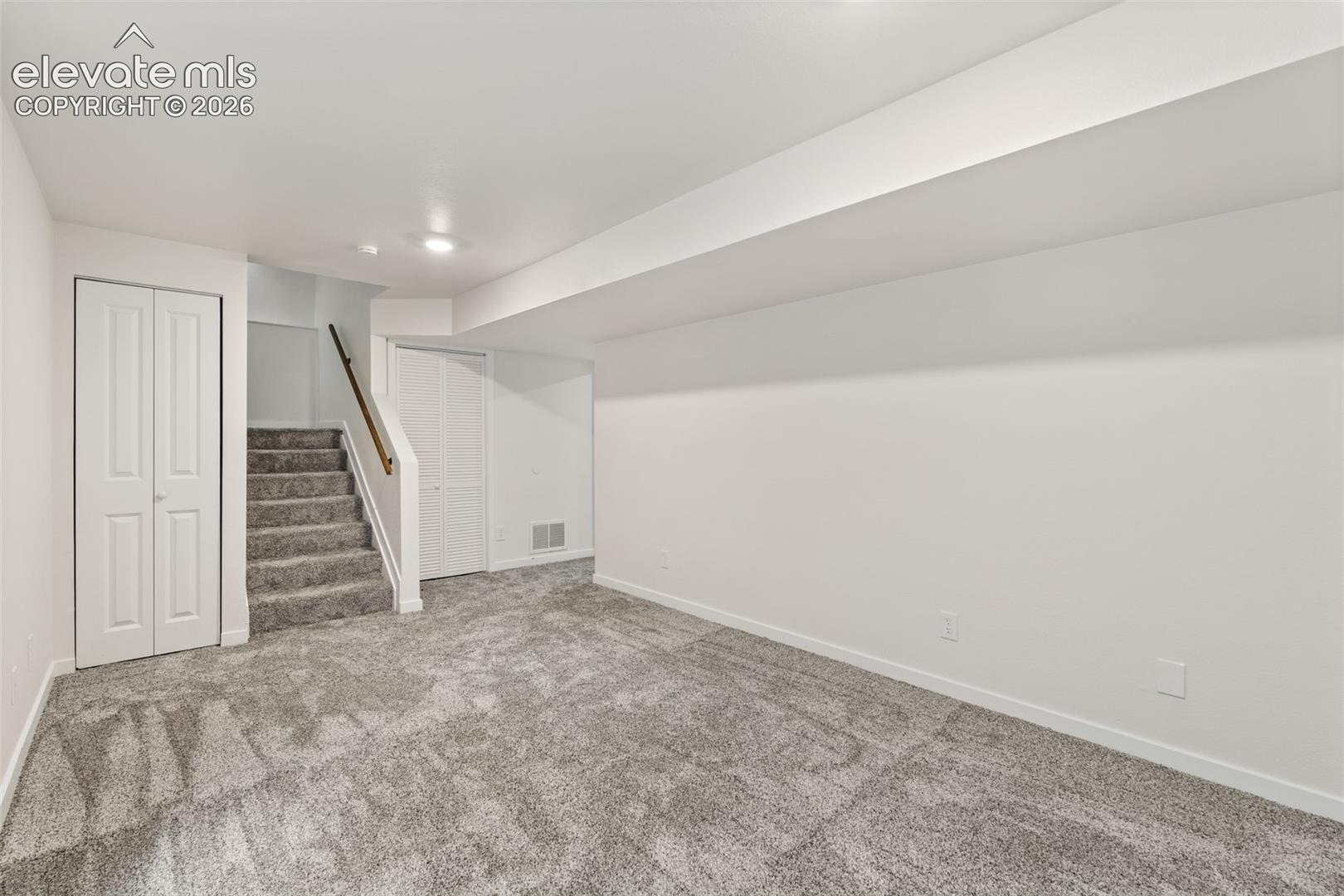 Open-concept interior space featuring wall-to-wall carpeting, recessed lighting, and bi-fold closet doors
