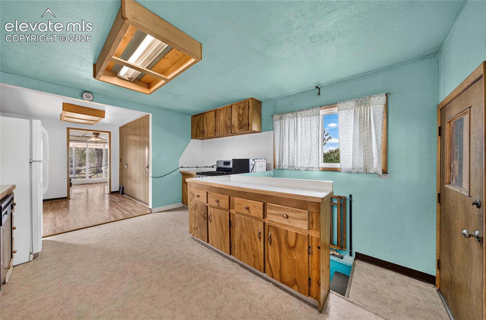 Kitchen featuring wood cabinetry, white countertops, a built-in oven, and overhead fluorescent lighting