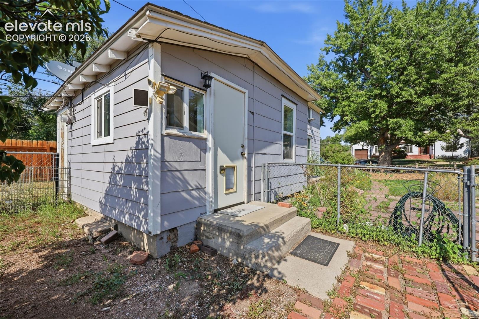 Exterior featuring, horizontal siding, white trim windows, a side door yard access, and brick paving.