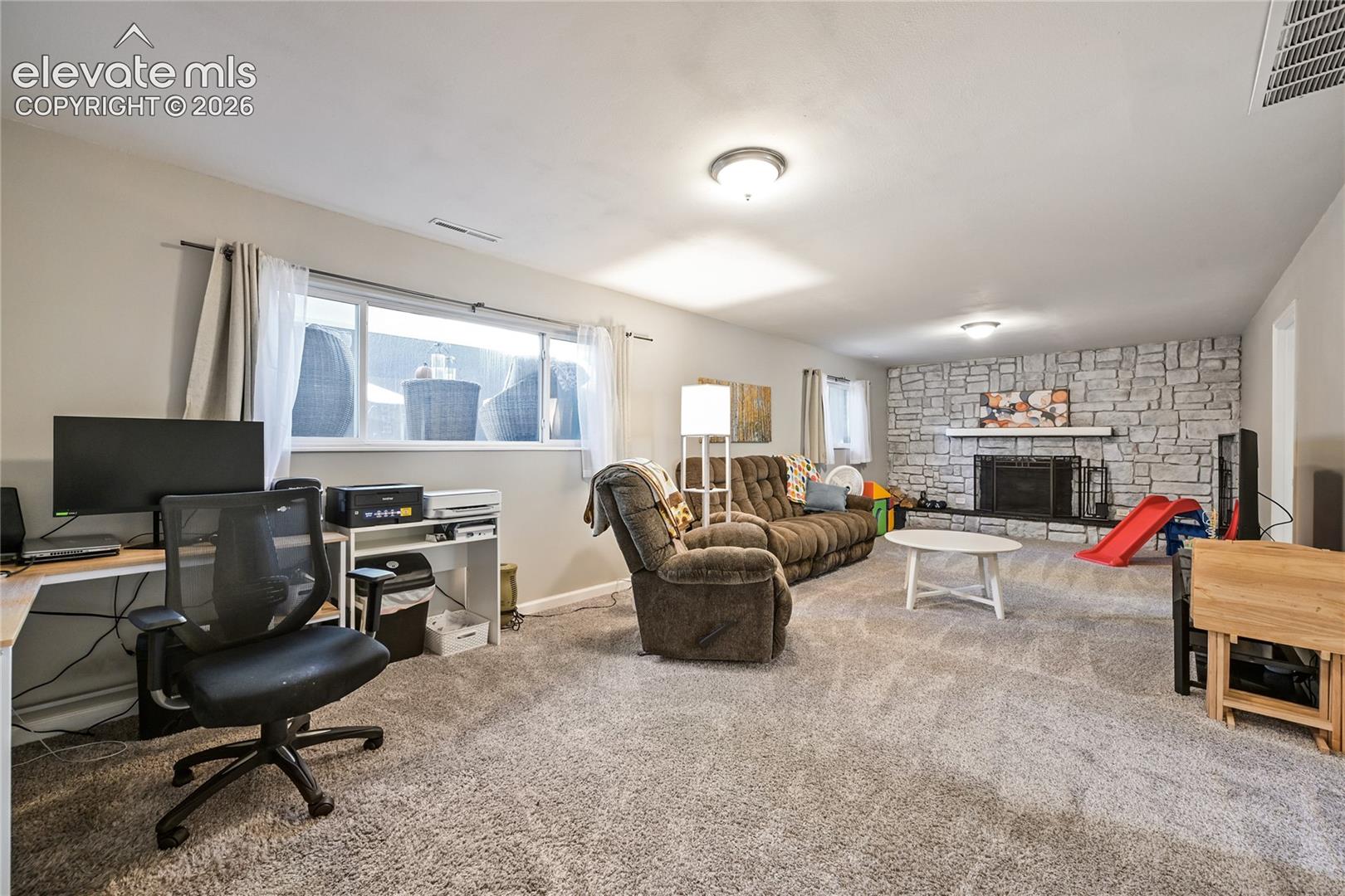 Expansive living area featuring stone-clad wall, built-in fireplace, wall-to-wall carpeting, and horizontal sliding windows