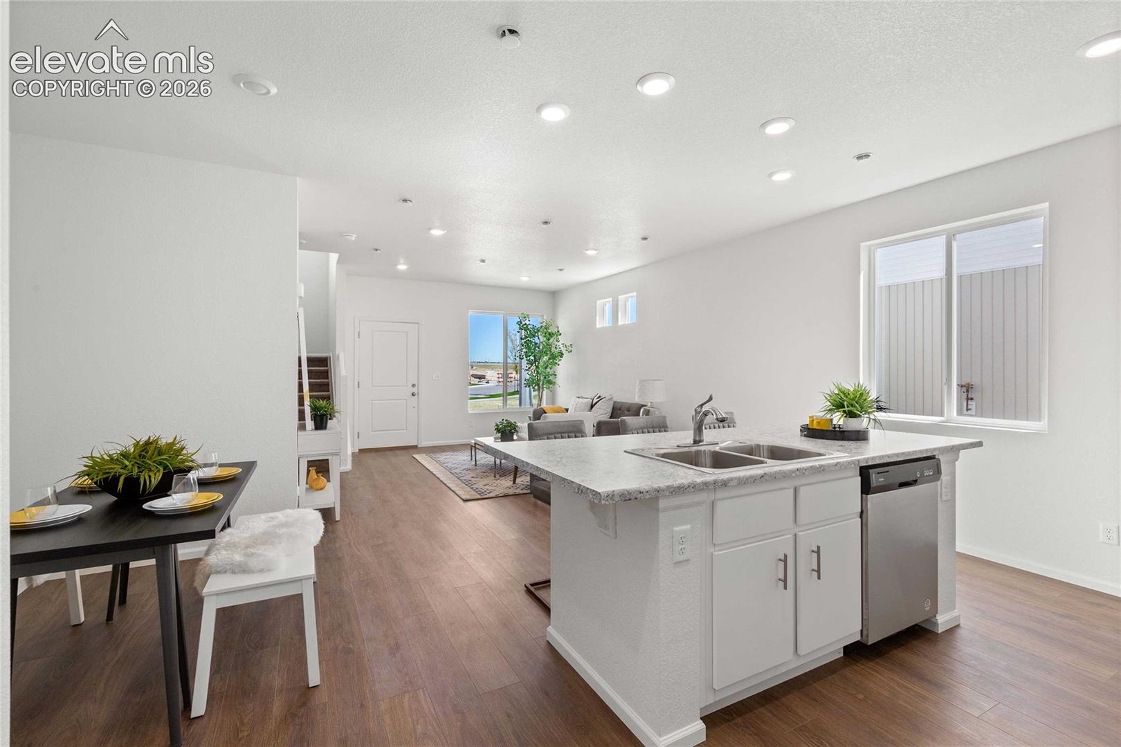 Kitchen island with double basin sink, stainless steel dishwasher, and light-colored countertops
*photos  of a model home*