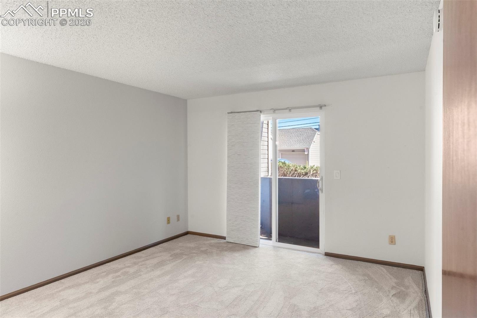 Empty room with a textured ceiling and light carpet