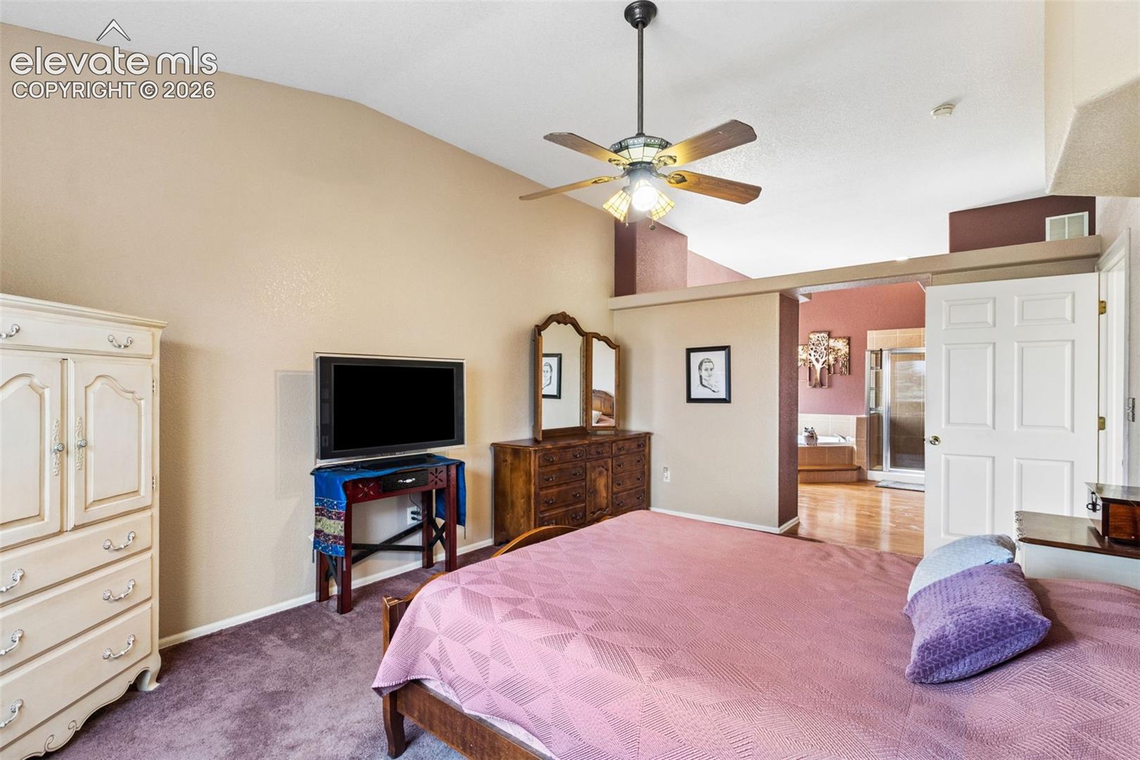 Vaulted ceilings, central ceiling fan, neutral wall paint, and traditional multi-panel interior door