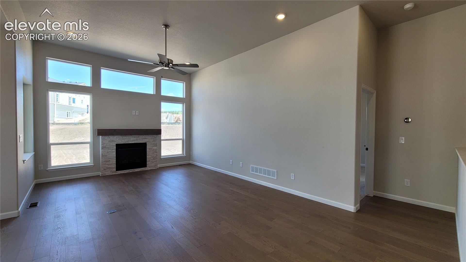 Great Room with engineered wood flooring, floor outlet, LED lighting, ceiling fan, cozy gas fireplace with a wood mantel, and stacked stone surround! 