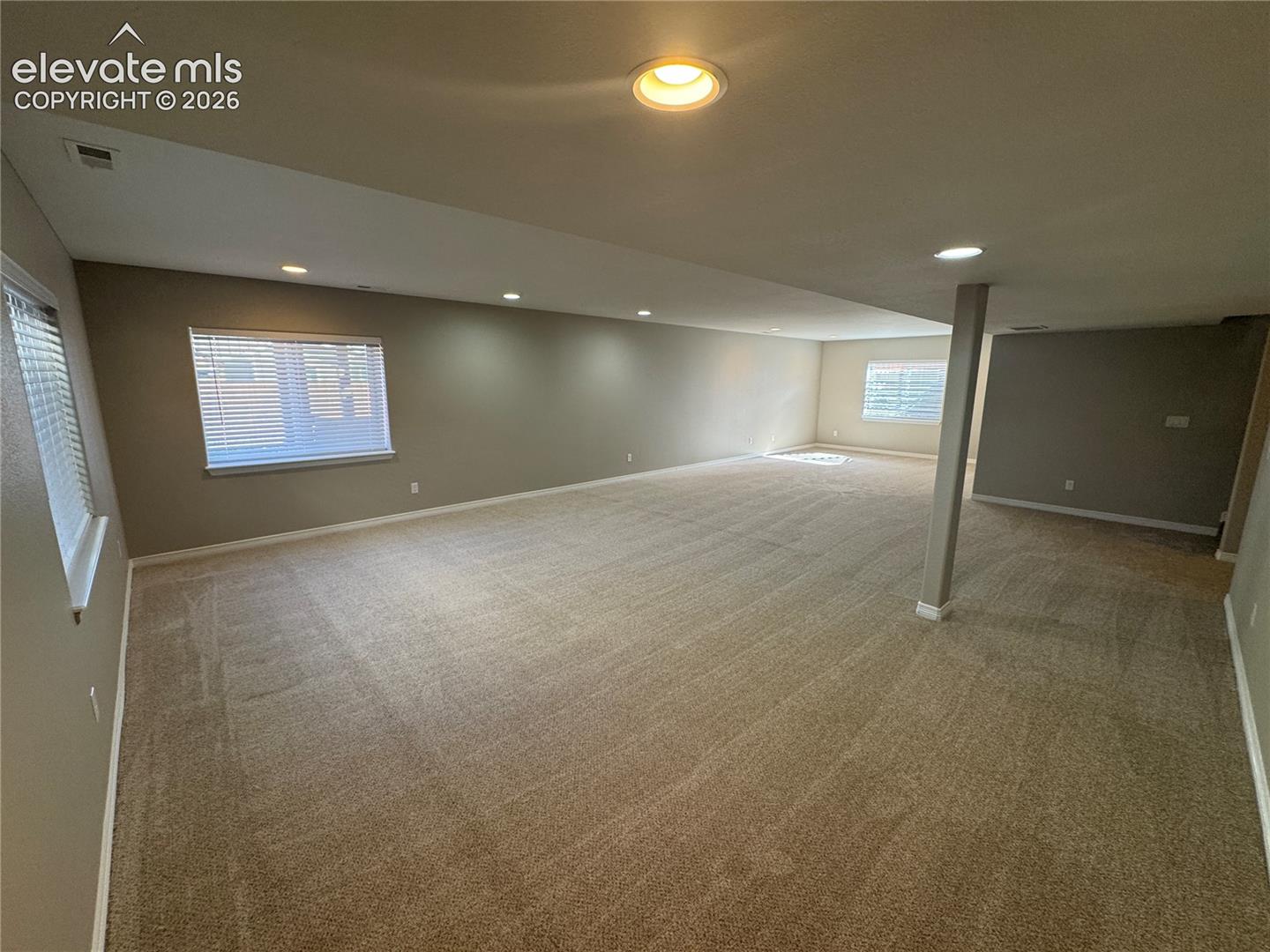 Expansive interior space featuring neutral wall tones, wall-to-wall carpeting, recessed lighting, and multiple windows
