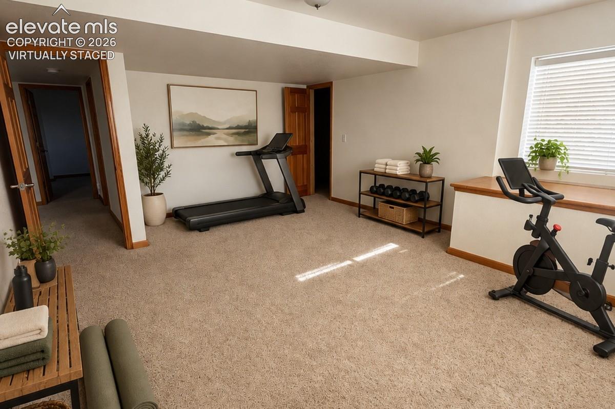 Carpeted room featuring a window with blinds, wood-trim doorways, and a built-in wood-finish window bench. Virtually staged.