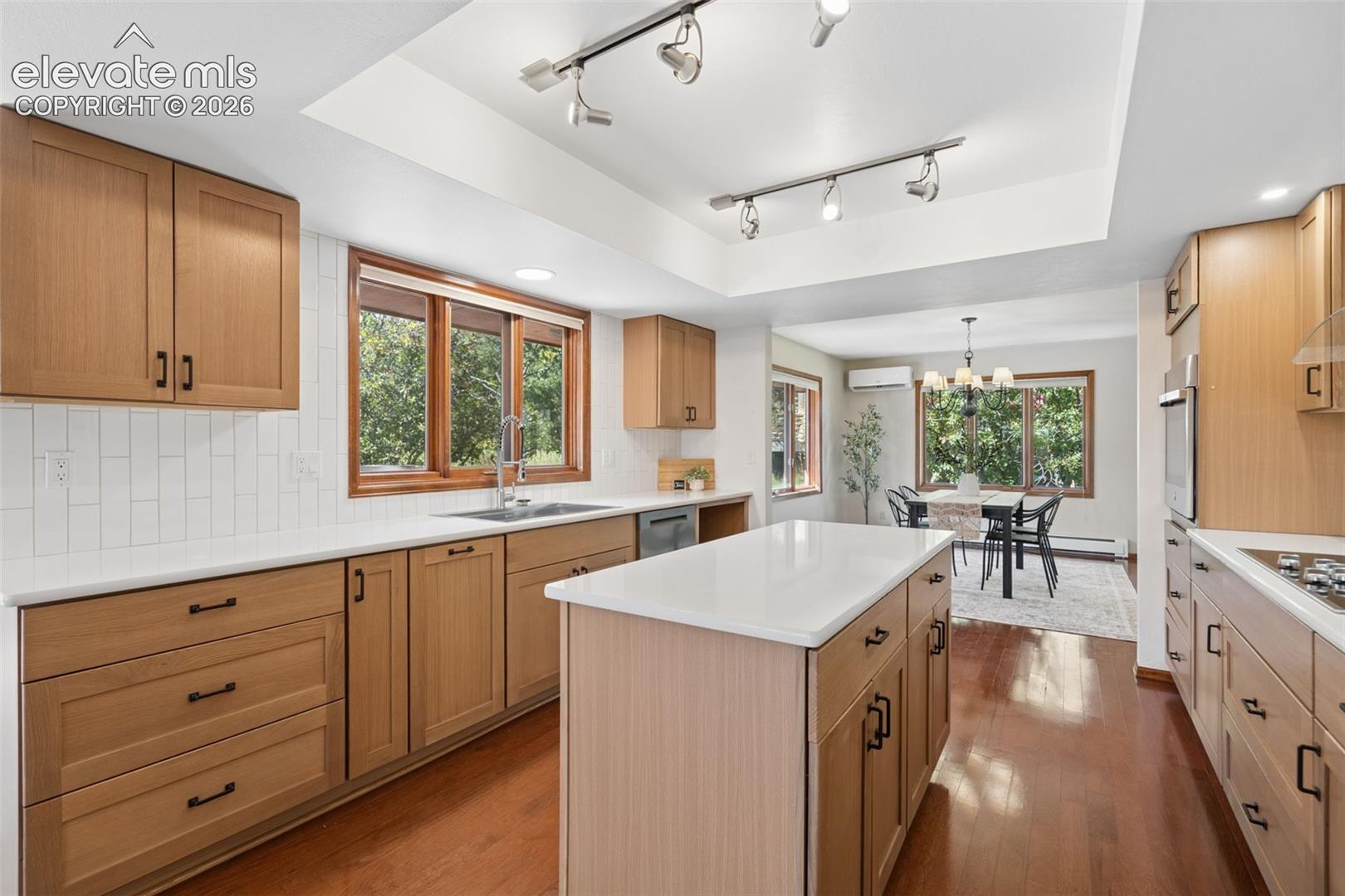 Kitchen featuring wood-finish cabinetry, white countertops, a center island, and a subway tile backsplash