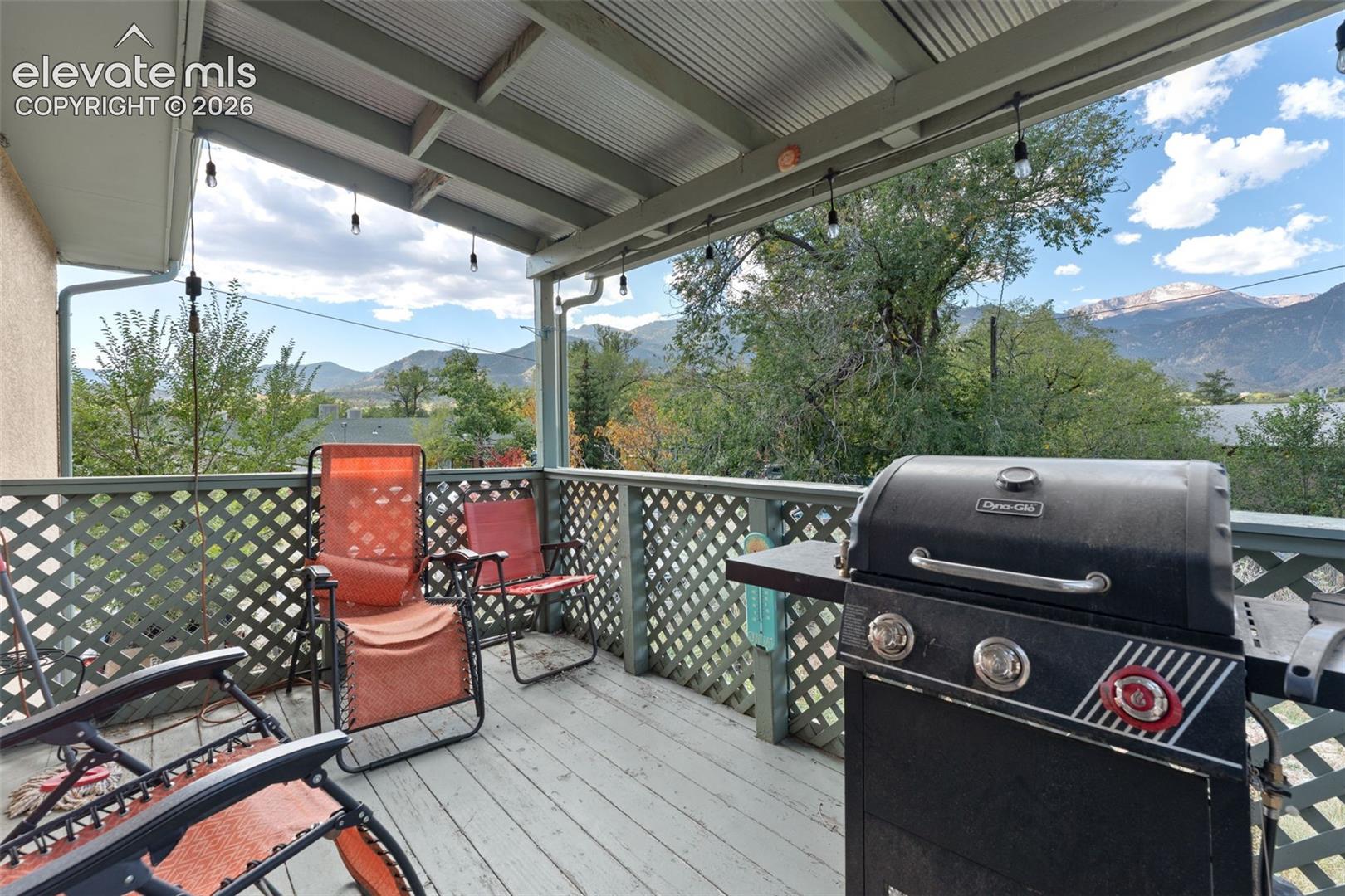 Covered outdoor deck with lattice railing, wood-finish flooring, and mountain backdrop