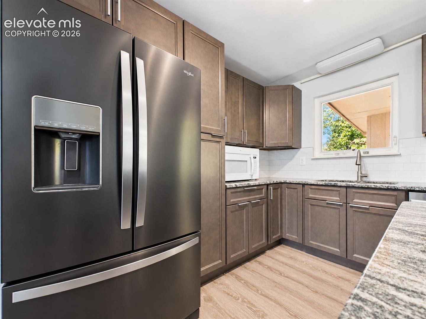 Ample cabinetry surrounds the French-door refrigerator and microwave area, providing plentiful kitchen storage and a cohesive updated finish.