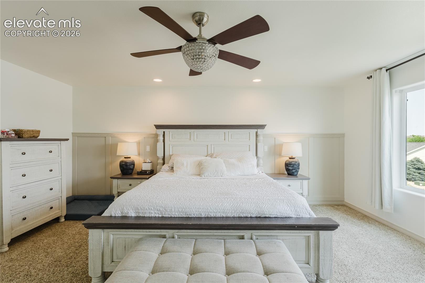Bright interior room featuring a decorative crystal ceiling fan, recessed lighting, and wall paneling