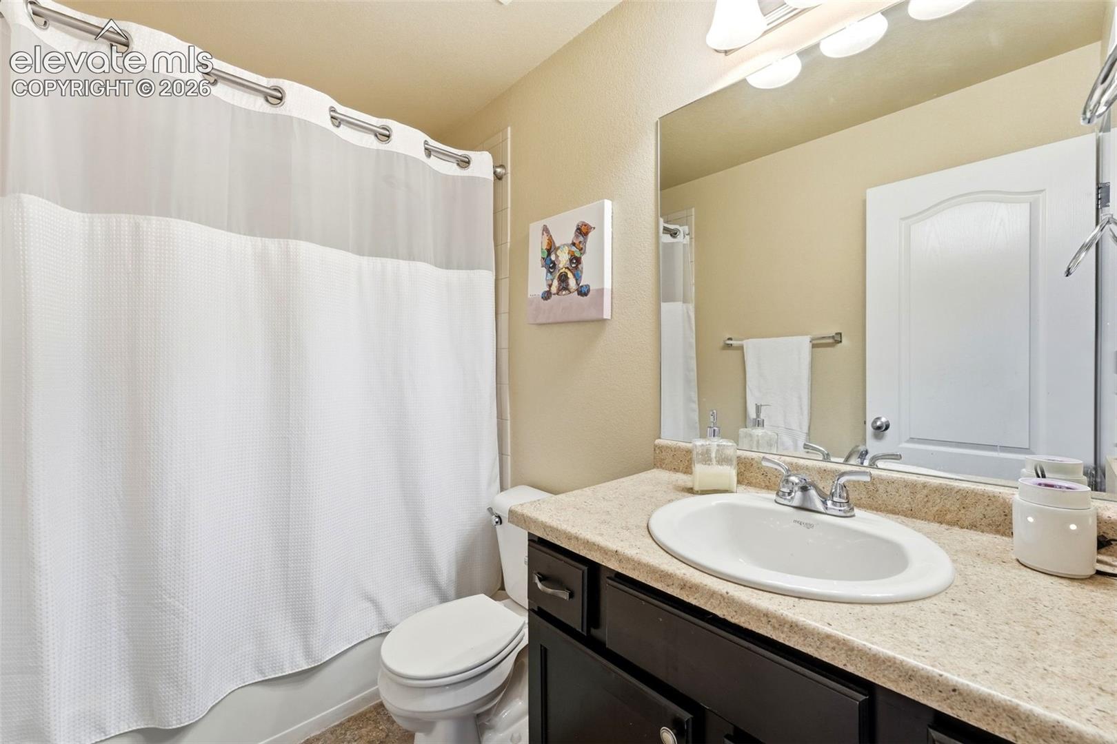 Bathroom featuring a single vanity, laminate countertop, dark wood-finish cabinetry, and a framed wall mirror