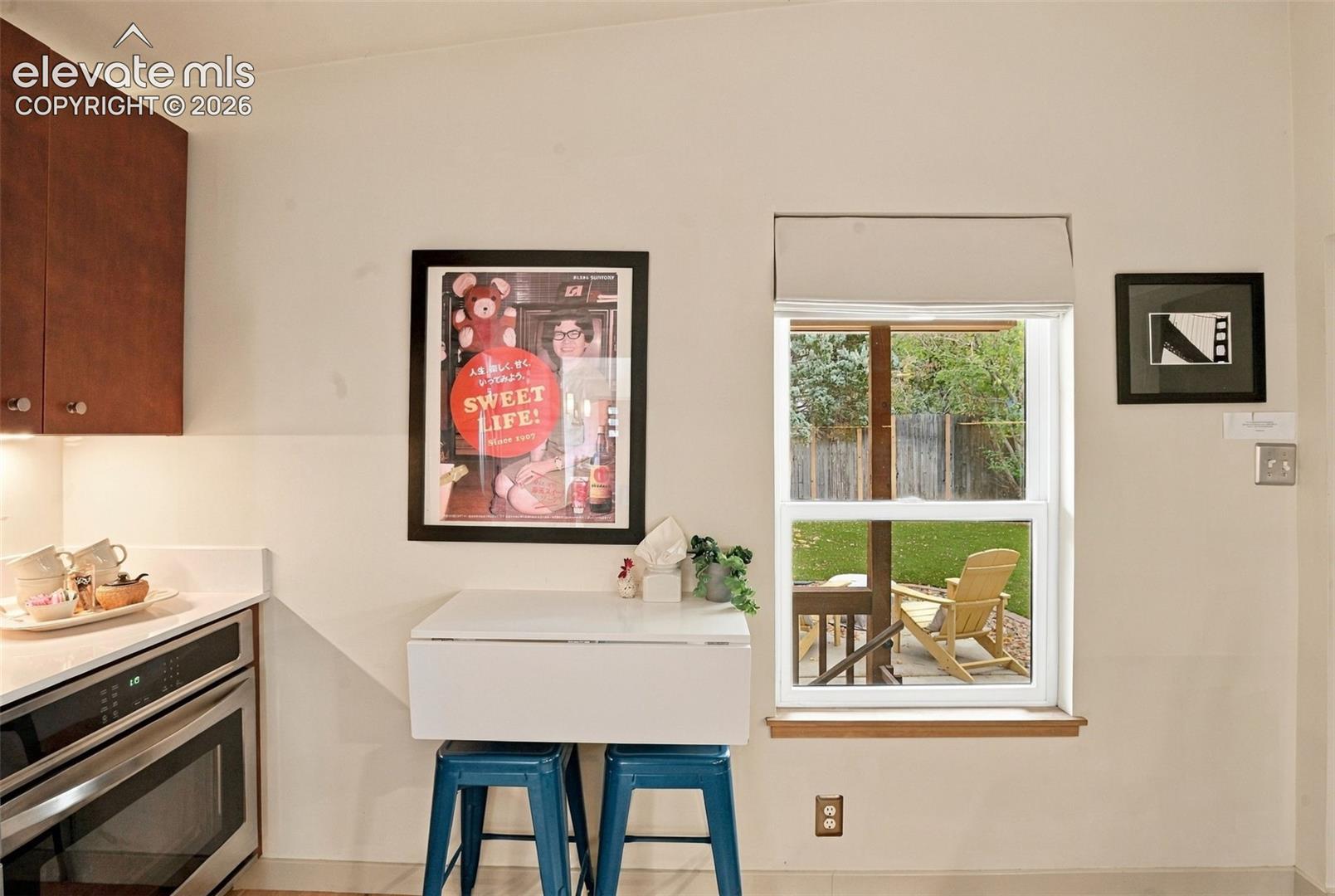 Kitchen area featuring wood-finish cabinetry, solid-surface countertops, a stainless steel built-in oven, and a double-pane window