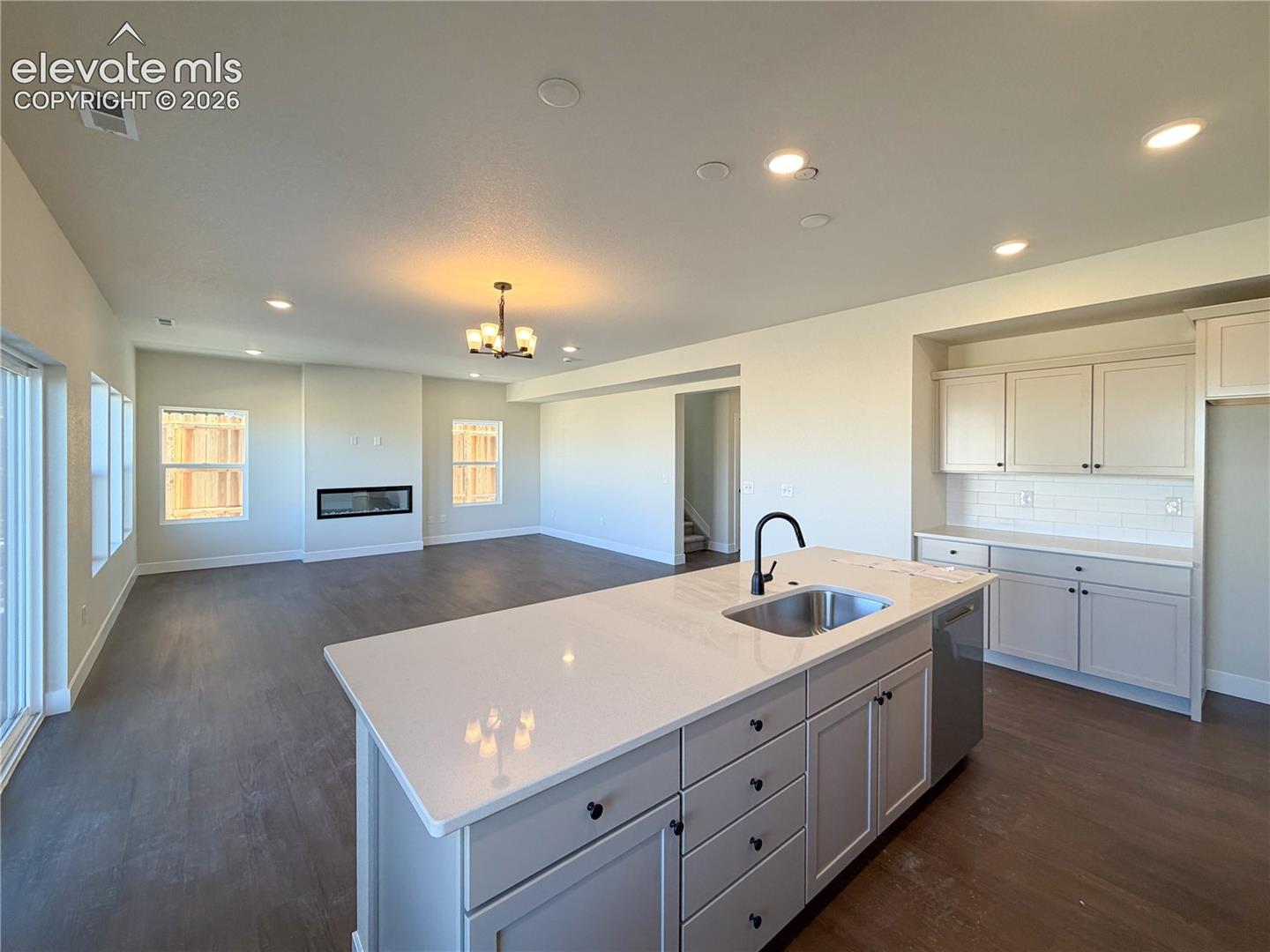 kitchen island with undermount sink and faucet, open to a living area with inset linear fireplace and two windows
