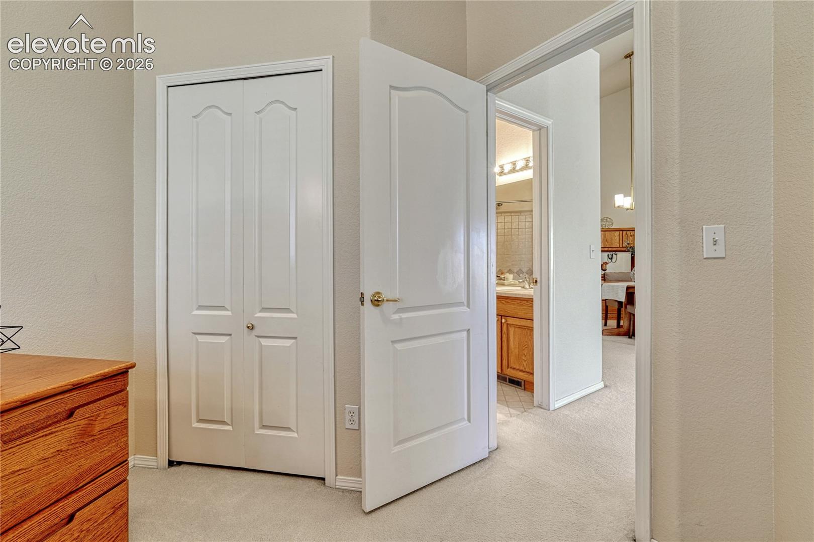 The main hallway connects living spaces with clean neutral carpeting, bi-fold closet doors, and smooth traffic flow throughout
