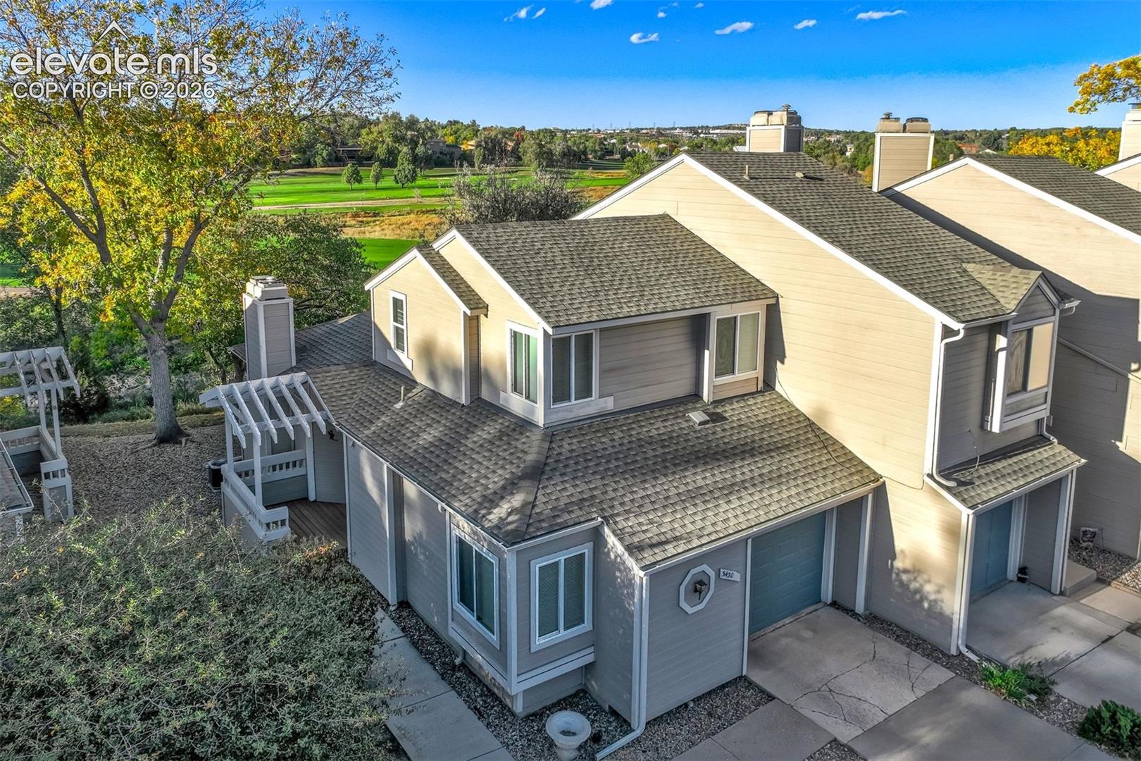 Multi-level exterior featuring light-toned horizontal siding, asphalt shingle roofing, integrated garage, and private outdoor pergola
