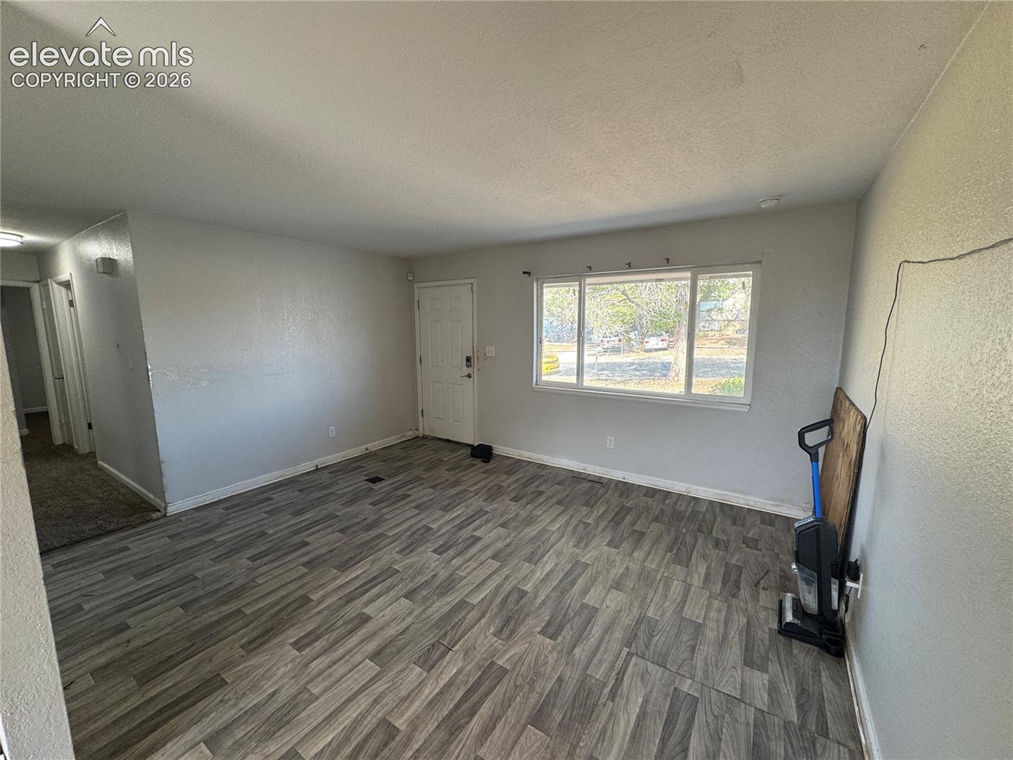 Wood-finish flooring throughout, bright white walls, and a large window providing ample natural light