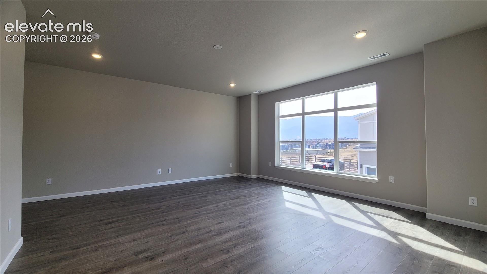 Living room with LVP flooring, LED lighting, Walk-Out to Composite Deck, and an abundance of natural light through the large window! 