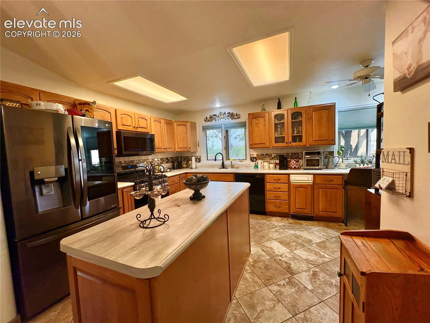 Kitchen featuring wood cabinetry, stainless steel appliances, a center island with a light-toned countertop, mosaic tile backsplash, and recessed lighting