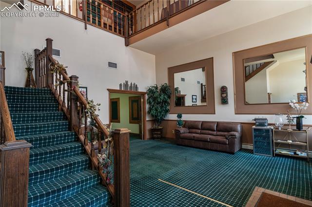 Living area featuring a towering ceiling, carpet floors, and stairway