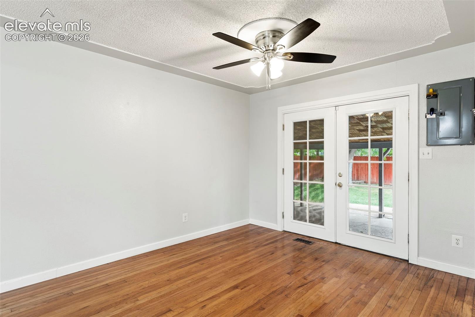 Wood-finish flooring with white trim, light gray walls, and a ceiling fan with integrated lighting