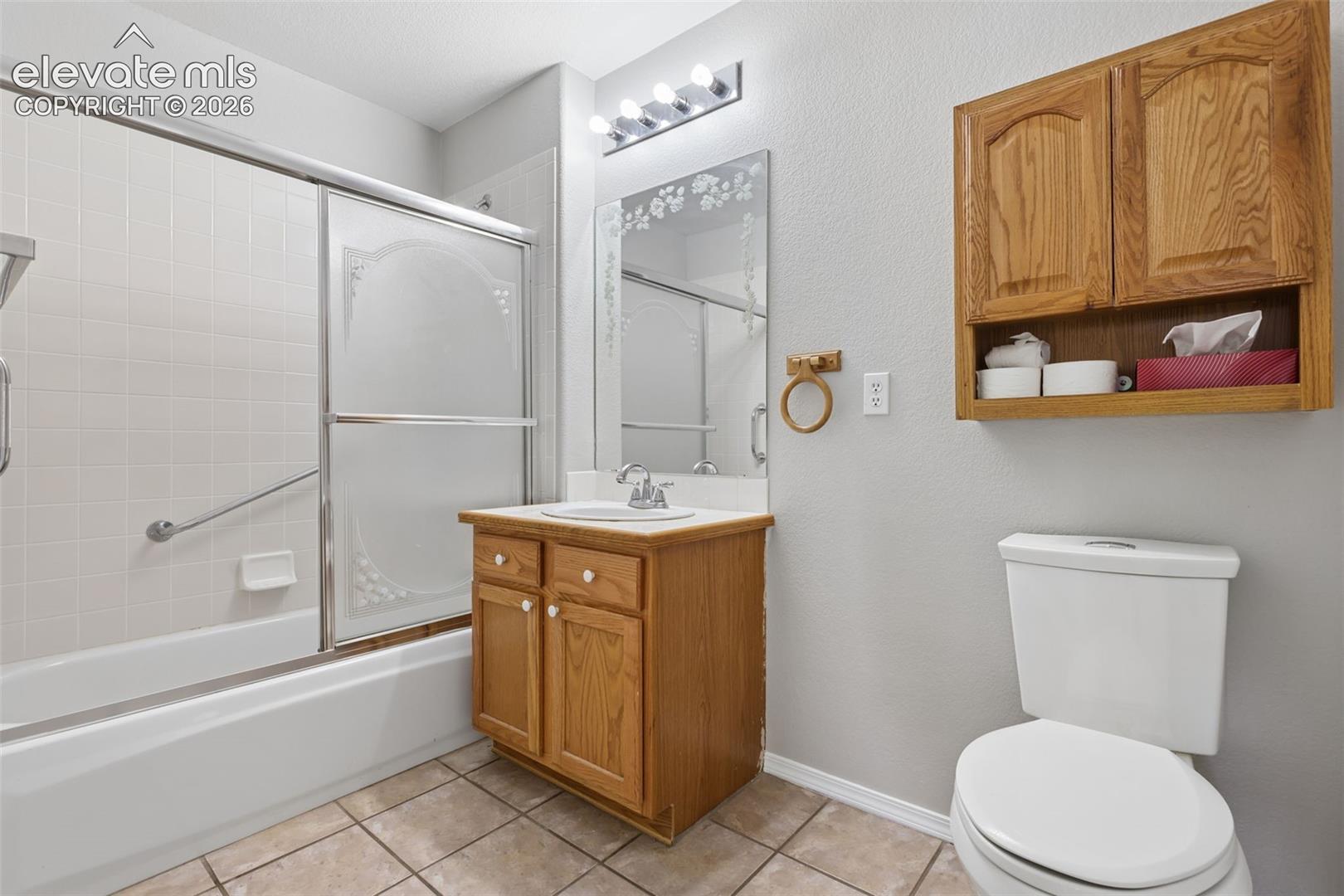 Bathtub with sliding glass doors, white tiled surround, and grab bar