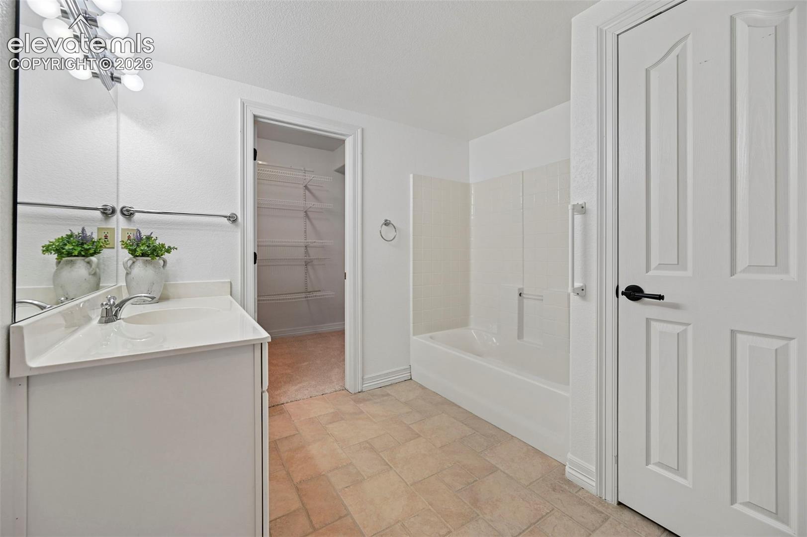 Bathroom vanity with integrated sink, chrome faucet, and overhead bar lighting