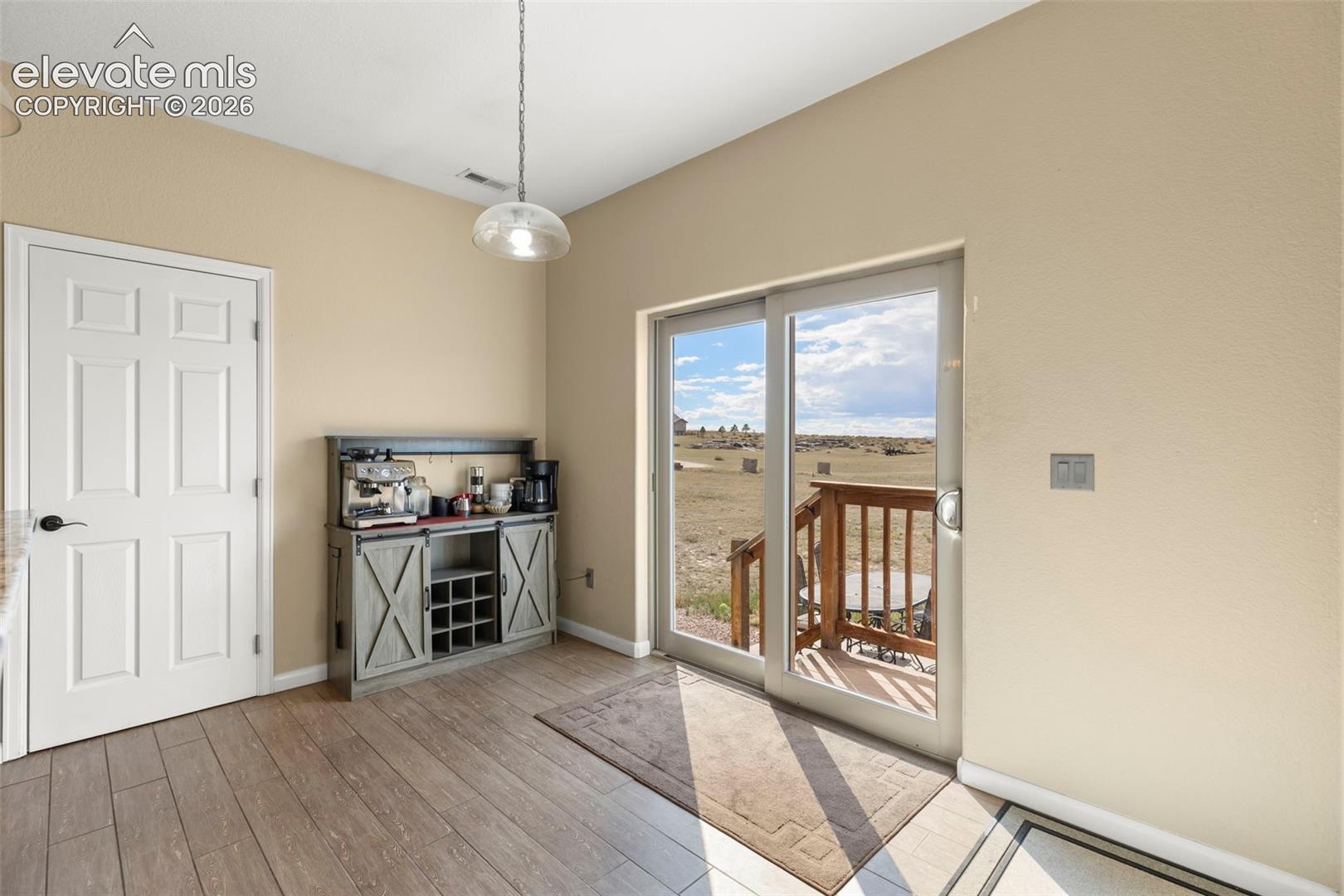 Wood-finish flooring, sliding glass door with exterior deck access, and ceiling-mounted pendant lighting