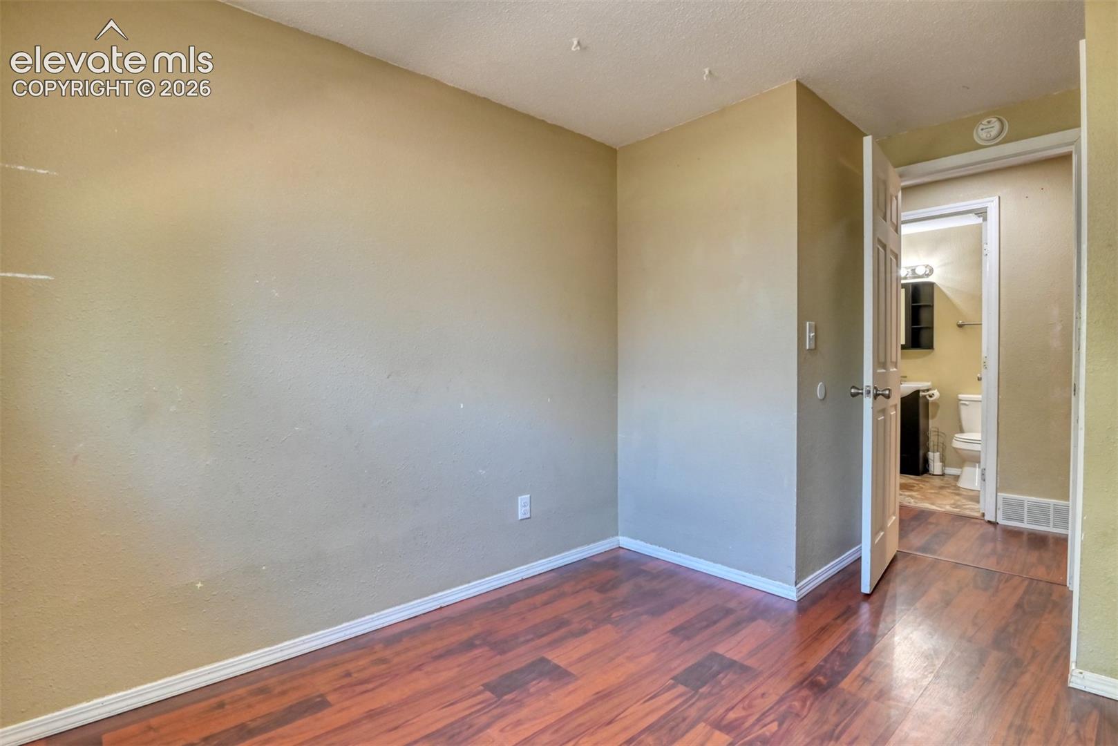 Room featuring neutral-toned walls, wood-finish flooring, and white baseboards