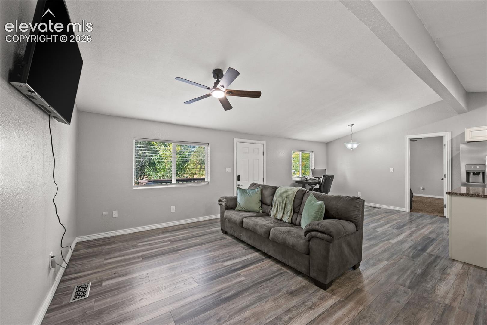 Vaulted ceilings, wood-finish flooring, recessed lighting, and a ceiling fan with integrated light fixture