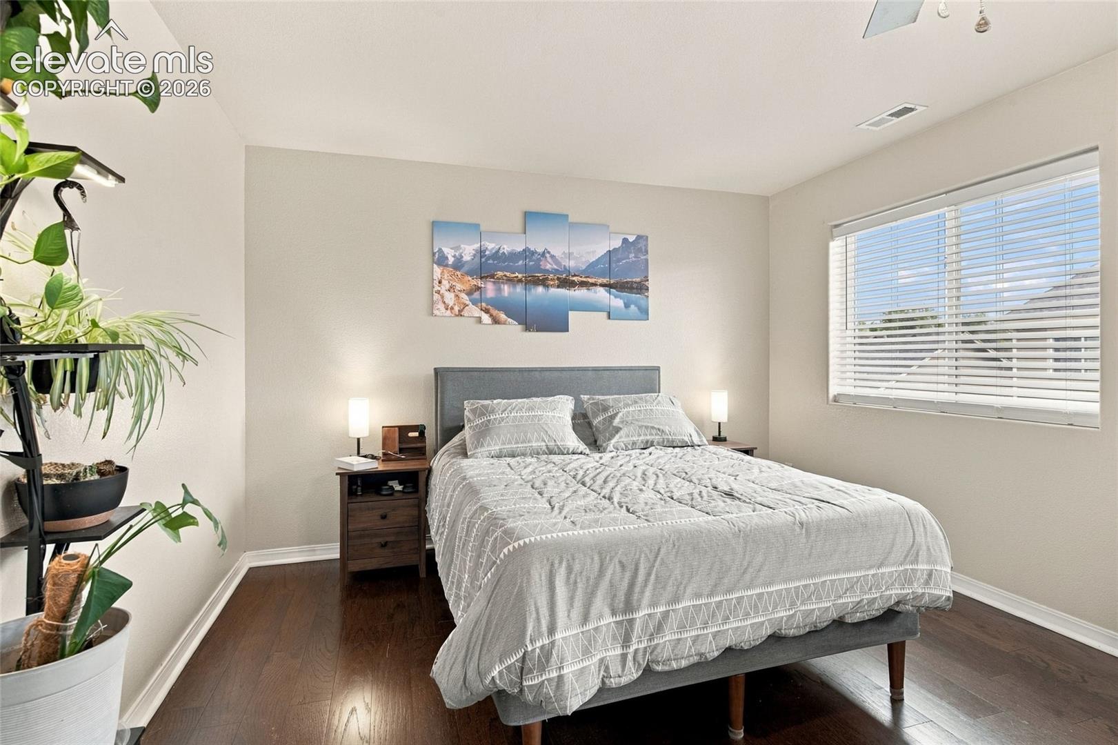 Dark-toned wood-finish flooring, neutral wall palette, and horizontal window blinds