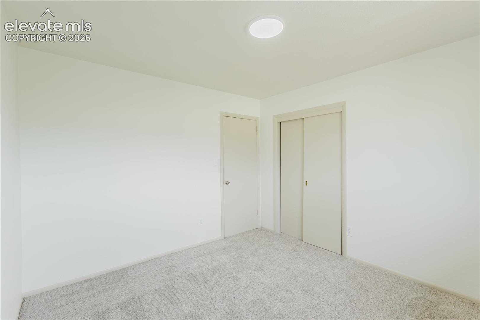 Interior room featuring light-colored carpeting, a recessed ceiling light, and a closet with sliding doors