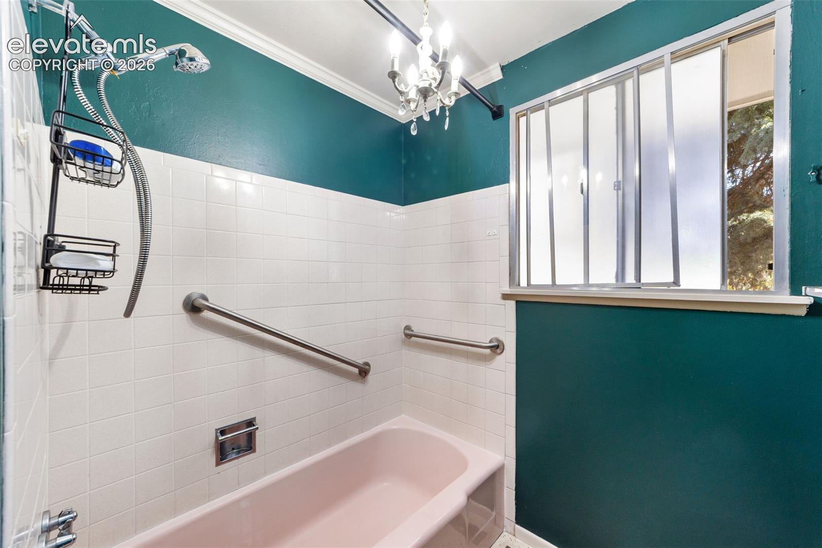 Bathroom featuring a pink bathtub, white tiled walls, and teal painted walls
