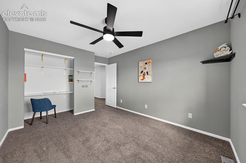 Dark gray carpeting, gray painted walls, and a black ceiling fan with integrated lighting