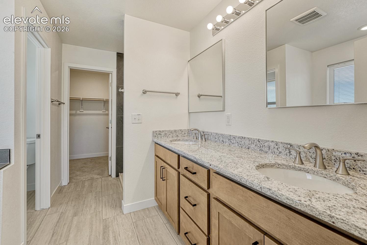 Attached 5-piece primary bathroom with granite counter and undermount sinks