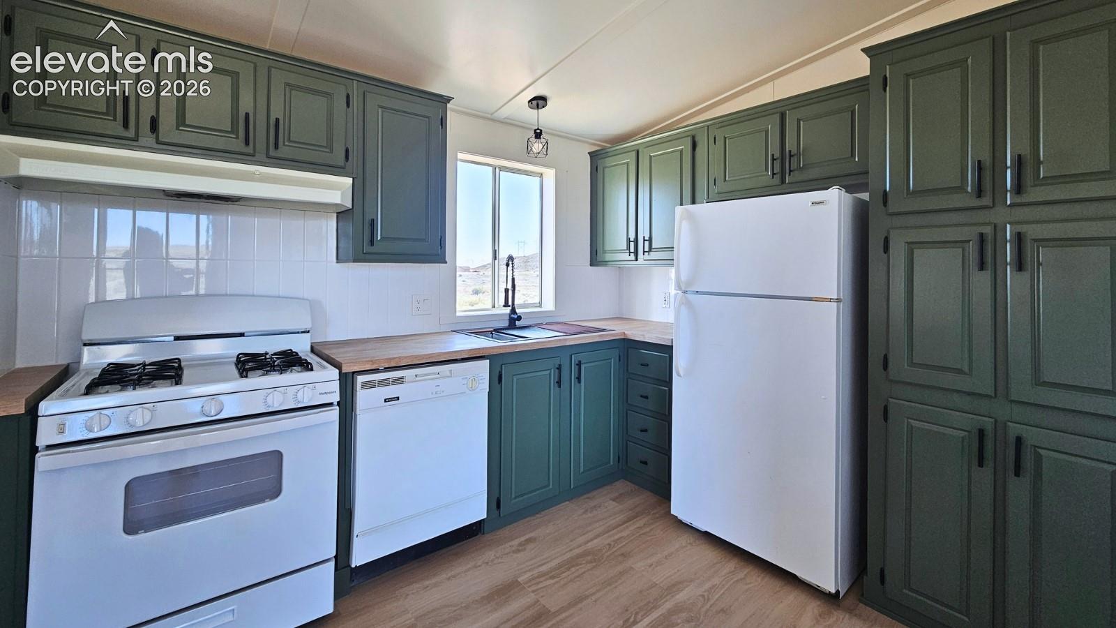 Kitchen featuring green cabinetry with matte black hardware, wood-finish countertops, tile backsplash, wood-finish flooring, and white appliances